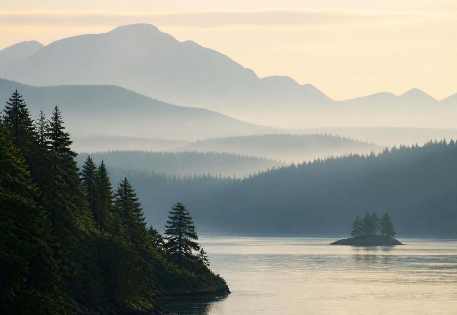 Misty mountains reflecting on calm water.